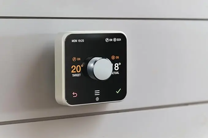 A smart thermostat mounted on a wall displaying a target temperature of 20 degrees and an actual temperature of 18 degrees, with a central control dial and various status indicators on the screen.